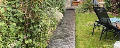 pathway through garden with greenery and patio furniture 